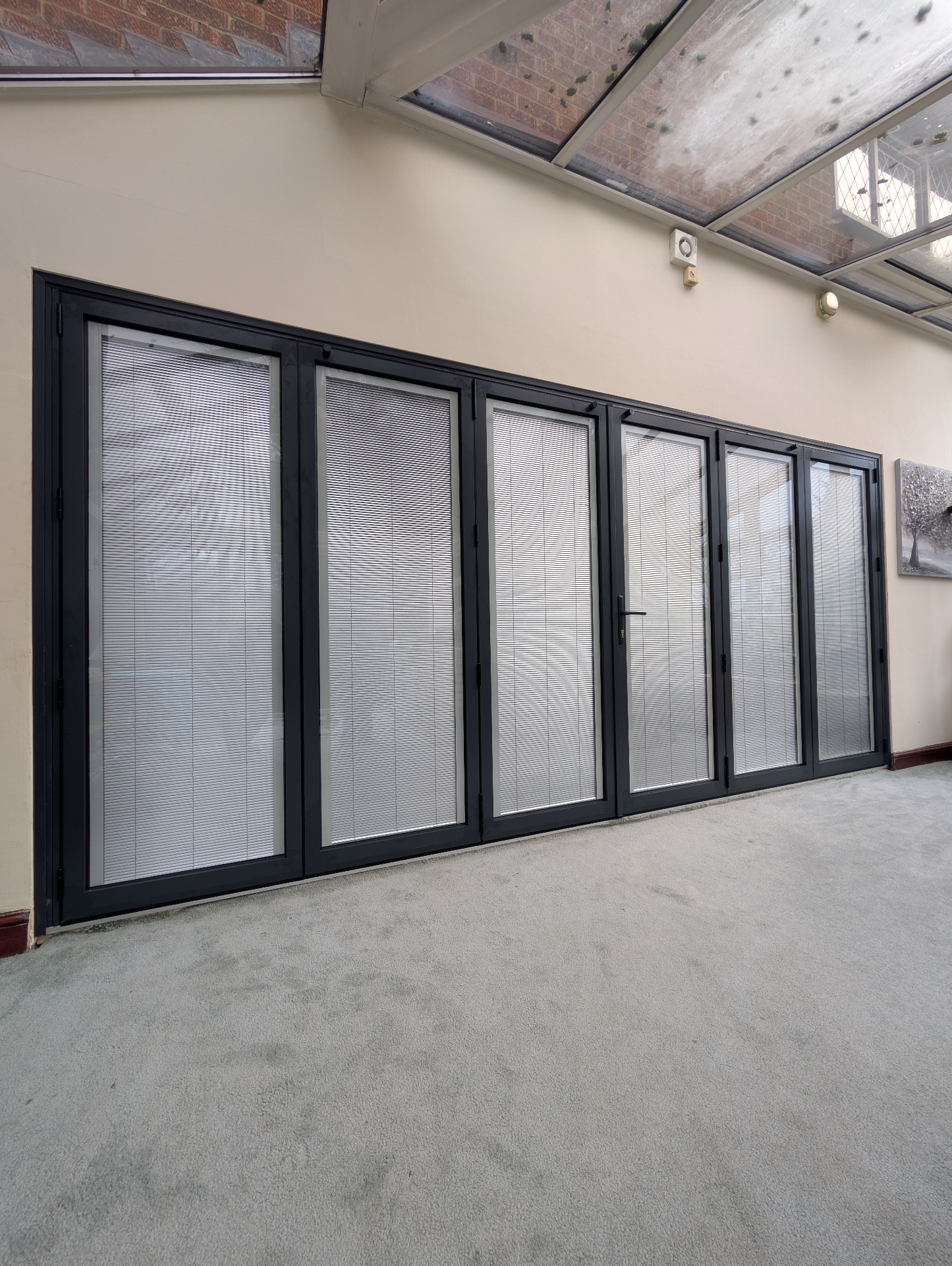 6-pane anthracite grey aluminium bifold doors with integral blinds in a conservatory
