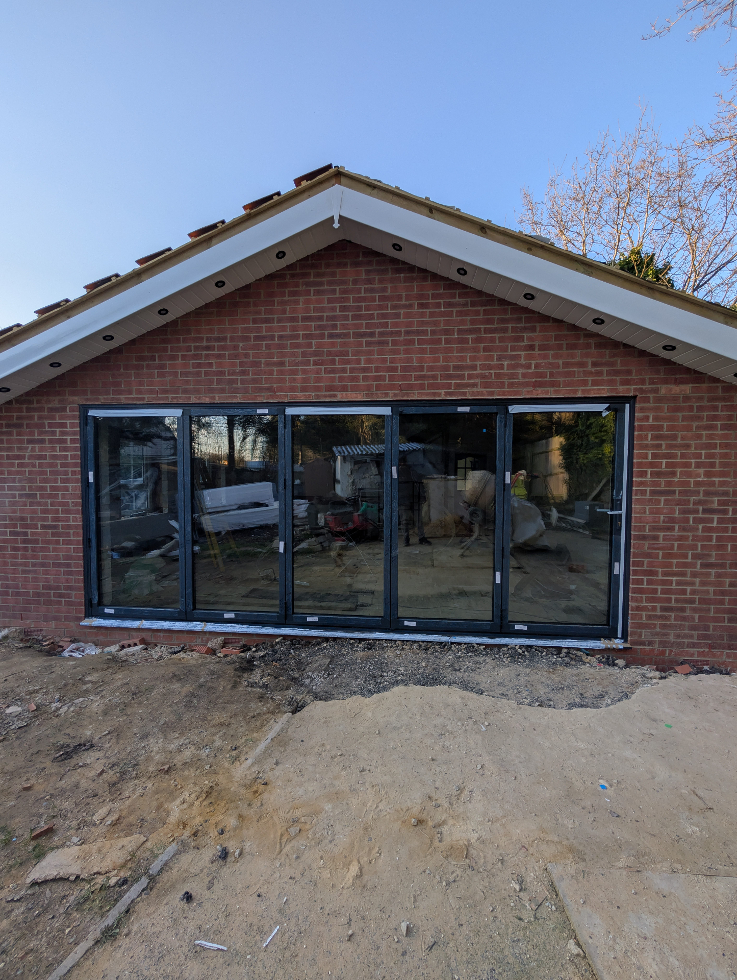 5-pane anthracite grey aluminium bifold doors installed on a brick gable extension